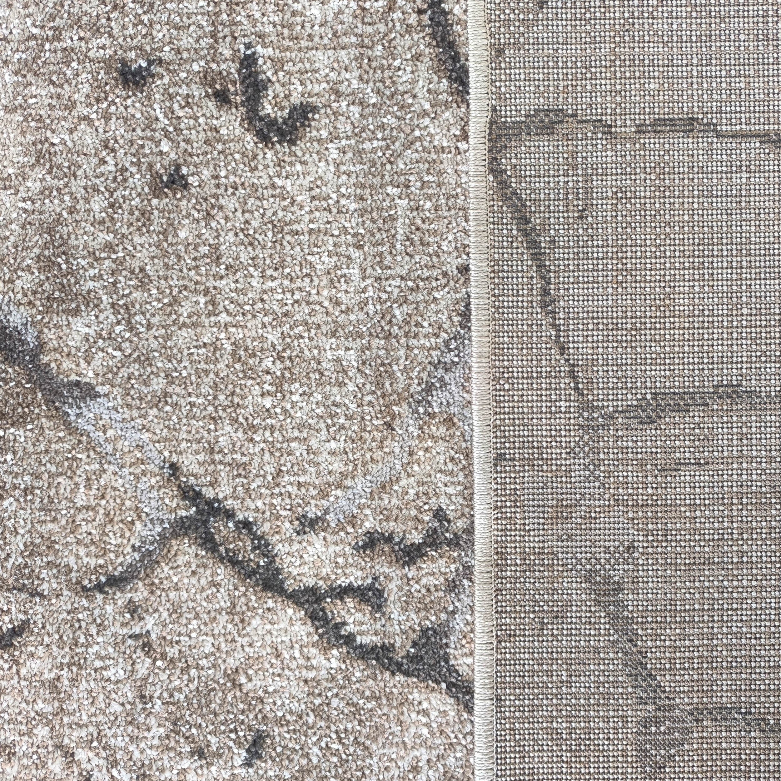 Moquette beige et grise à texture bouclée avec motifs abstraits, bordée d'un revers tissé plat moucheté marron