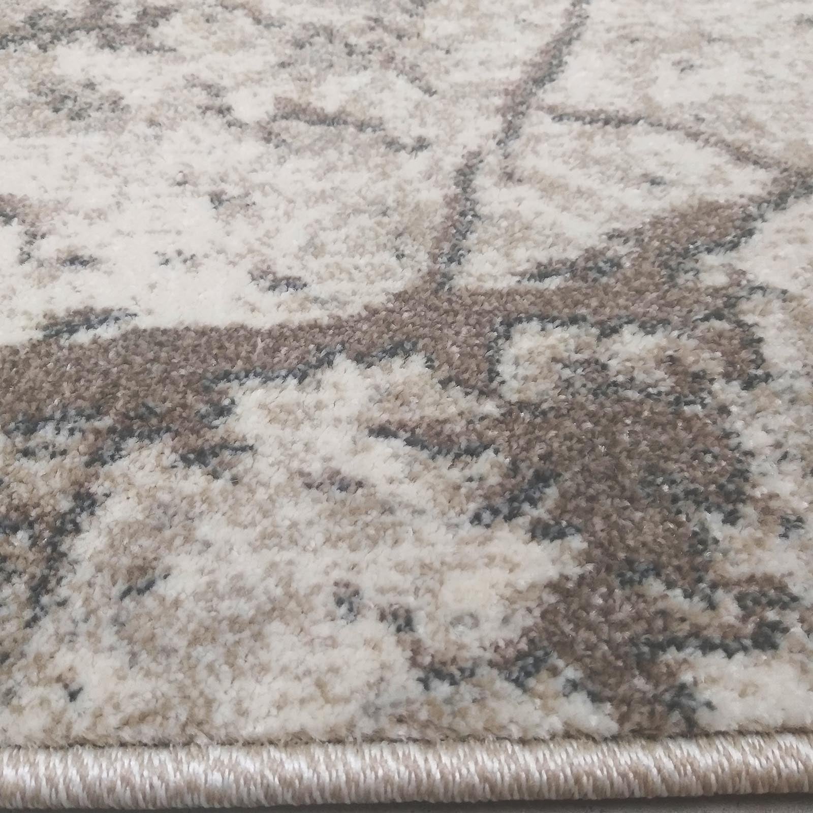 Gros plan d'un tapis aux motifs abstraits et irréguliers, beige, crème et marron, avec une bordure tressée