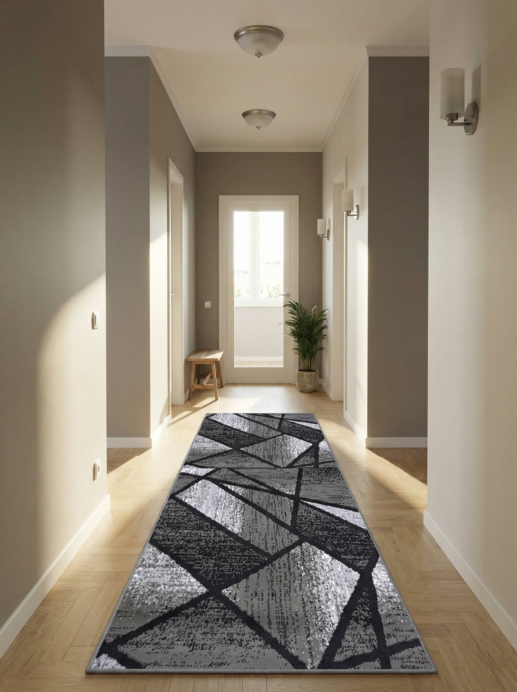 Tapis rectangulaire à motifs géométriques abstraits gris foncé, gris clair et noir, posé sur le parquet d'un couloir lumineux