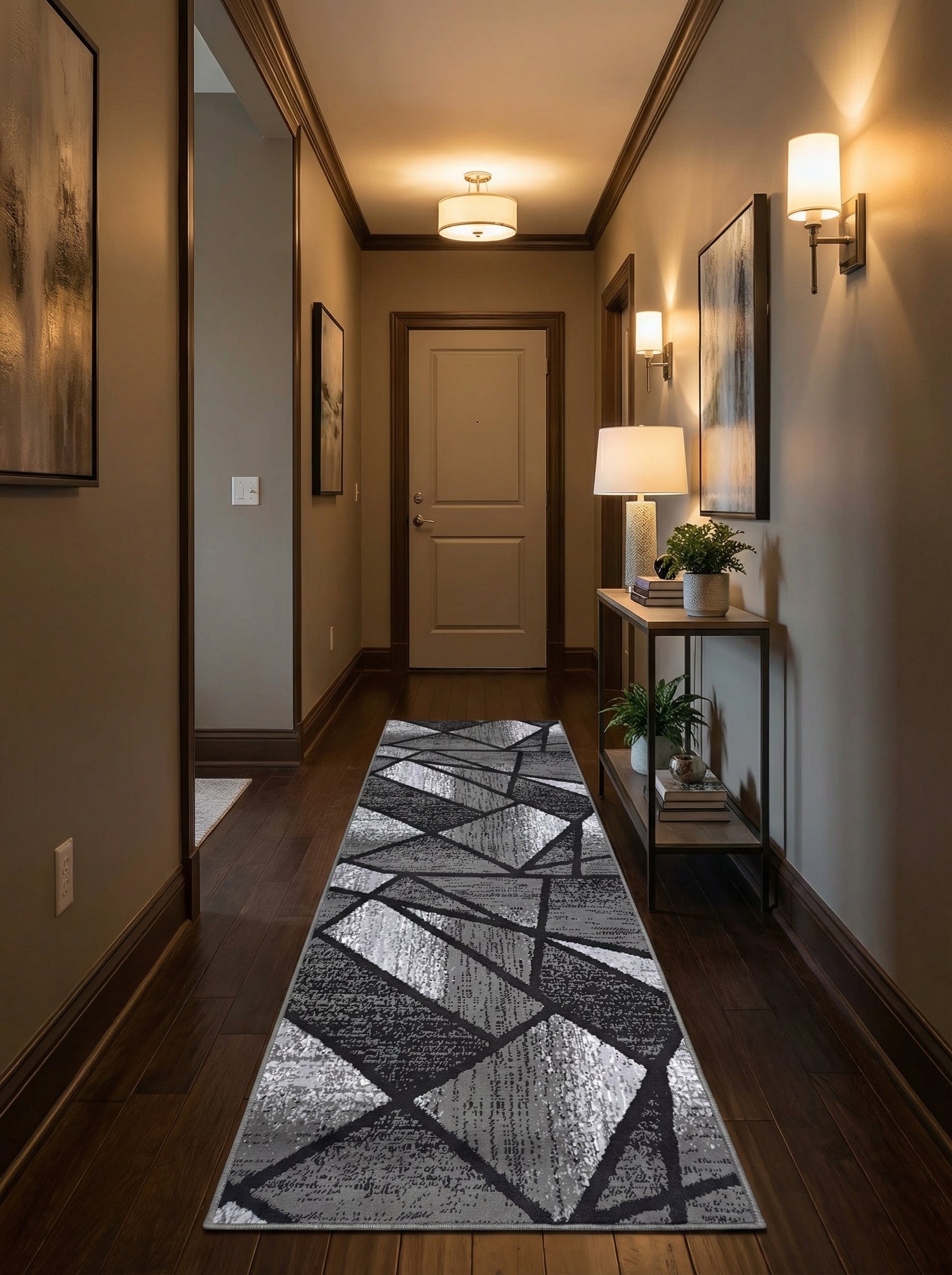 Tapis long à motifs géométriques abstraits en nuances de gris et noir, avec des zones claires texturées, posé sur un parquet foncé dans un couloir chaleureux