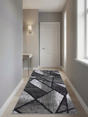 Grand tapis de couloir aux motifs géométriques abstraits gris, noirs et blancs, sur un sol en bois clair dans une entrée