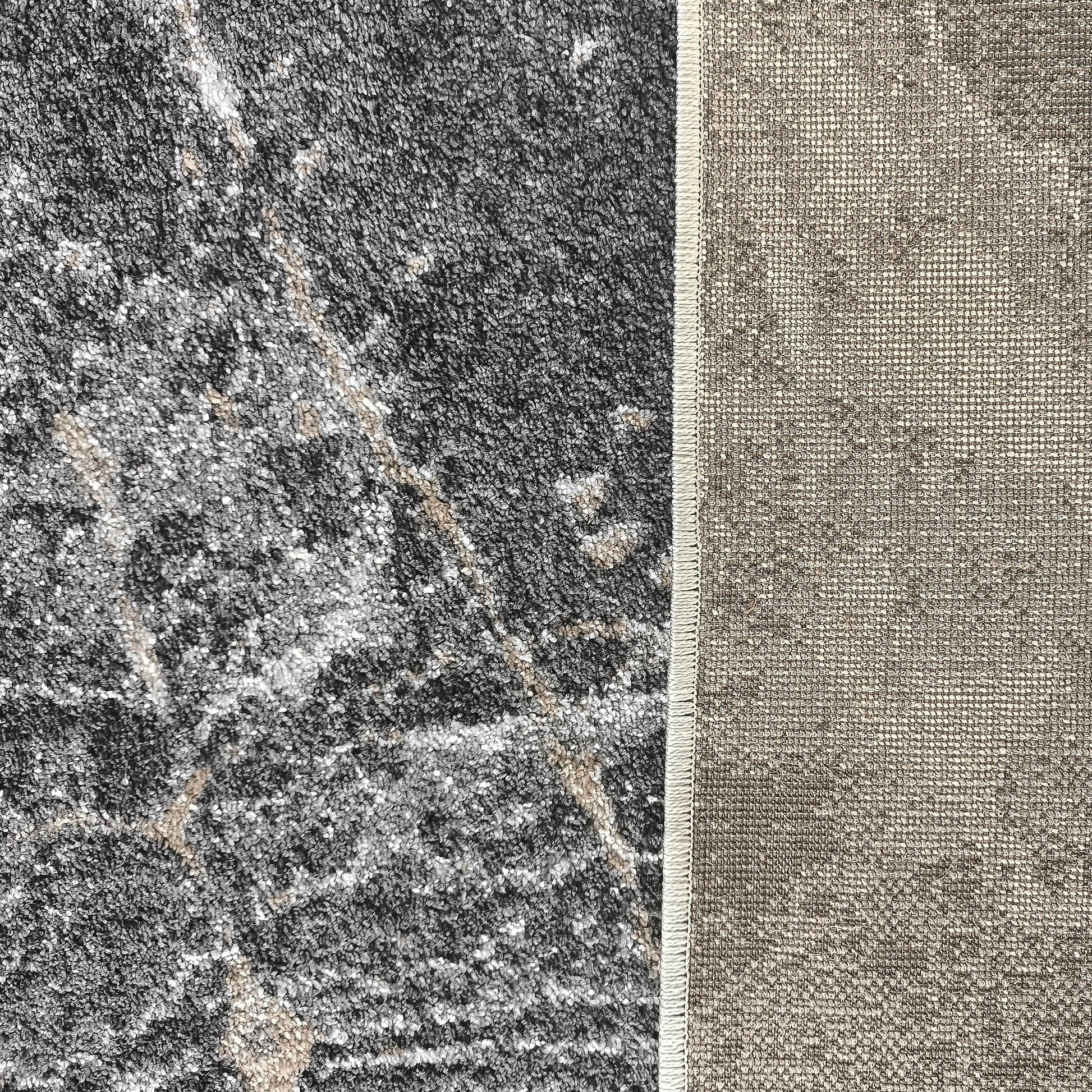 Dessus d'un tapis gris foncé moucheté de blanc et beige, avec un envers tissé beige et une bordure visible