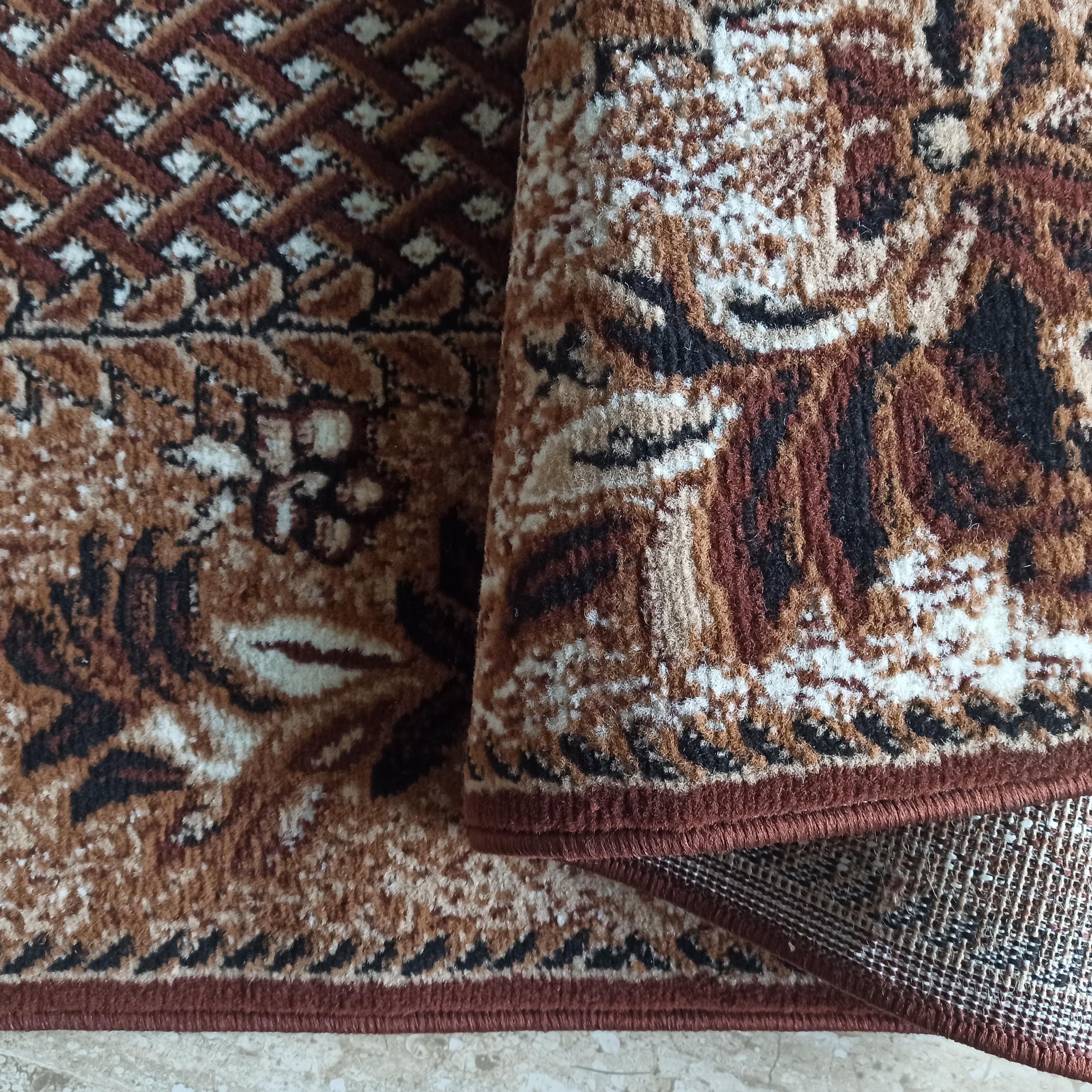 Tapis à la texture douce et aux motifs floraux et géométriques, dans les tons marron, beige, noir et crème