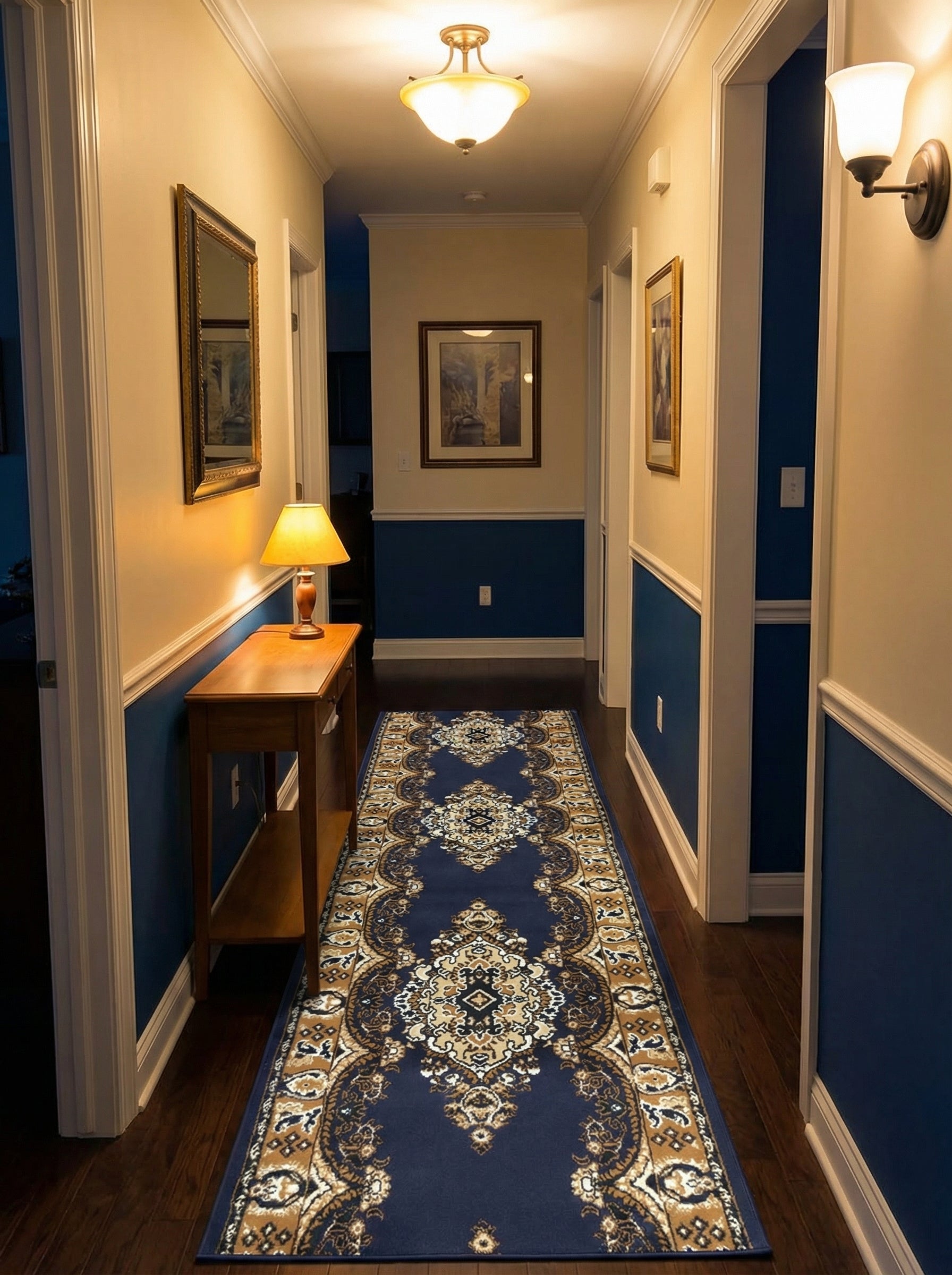 Long tapis de couloir bleu marine avec des motifs ornementaux dorés et crème, posé sur un parquet en bois foncé dans un hall d'entrée éclairé