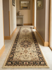 Un long chemin de tapis à motifs orientaux, crème, noir et bordeaux avec un médaillon central et une bordure foncée, posé sur un sol carrelé dans un couloir lumineux
