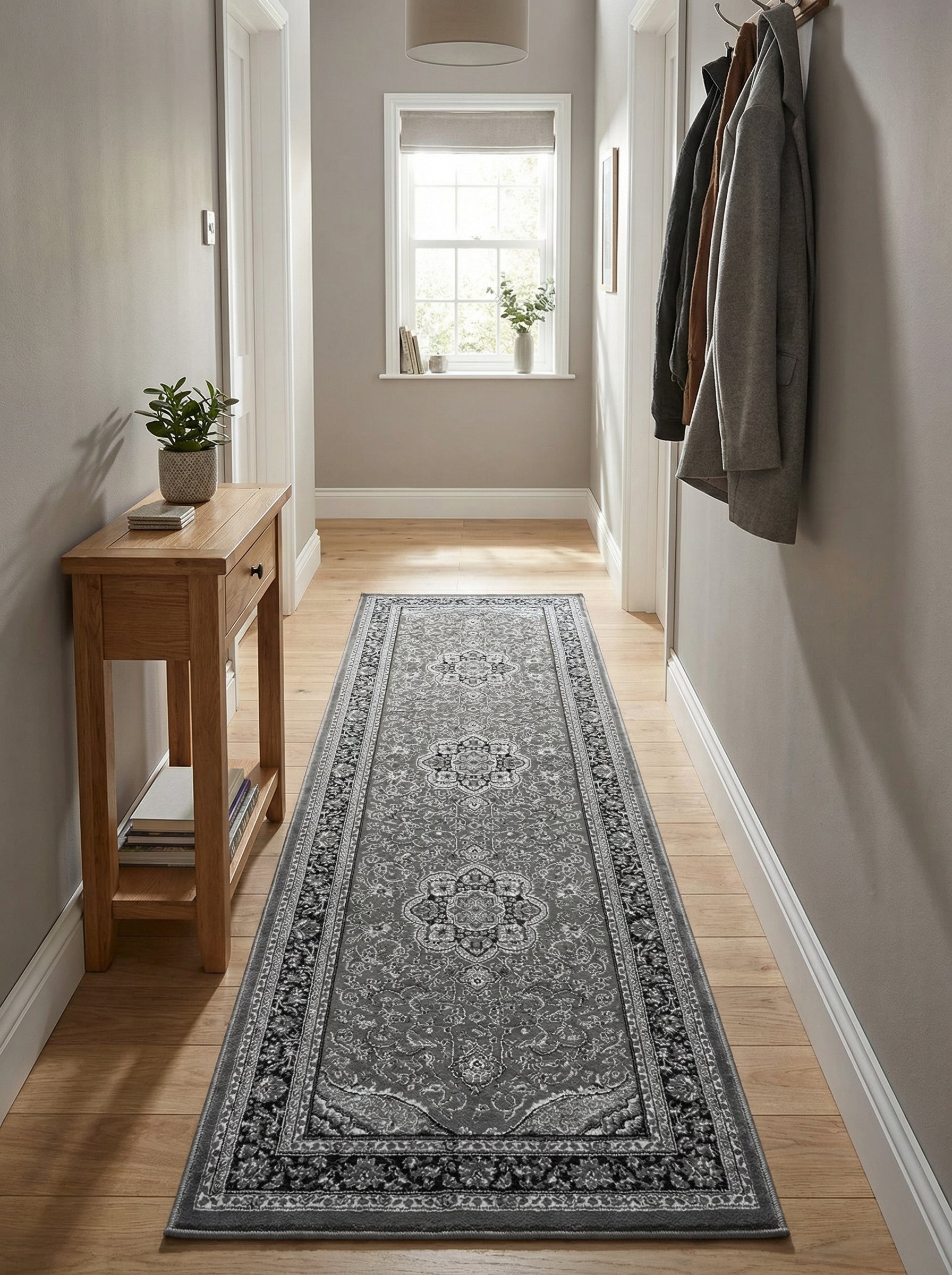 Tapis de cou couloir gris à motifs floraux et médaillons noirs et blancs, posé sur un parquet en bois clair dans un long couloir