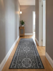 Tapis de couloir gris foncé à motifs ornementaux tissés en gris clair et noir, sur parquet dans un couloir