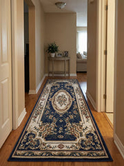 Long tapis bleu marine orné de motifs floraux beige, crème et rose, avec un médaillon central, posé sur un parquet dans un couloir
