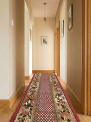 Tapis de couloir rouge avec motifs floraux beiges et noirs et un centre géométrique, dans un long couloir