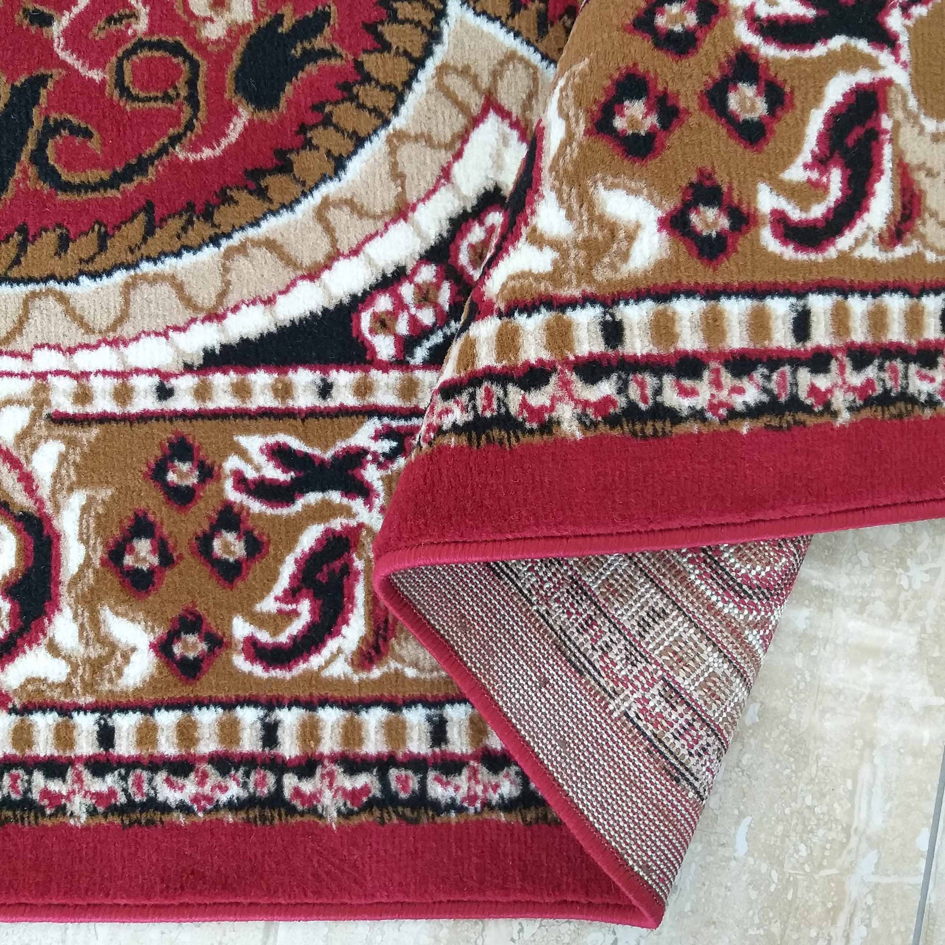 Tapis coloré rouge, marron, noir et blanc, à motifs floraux et arabesques, montrant son envers tissé