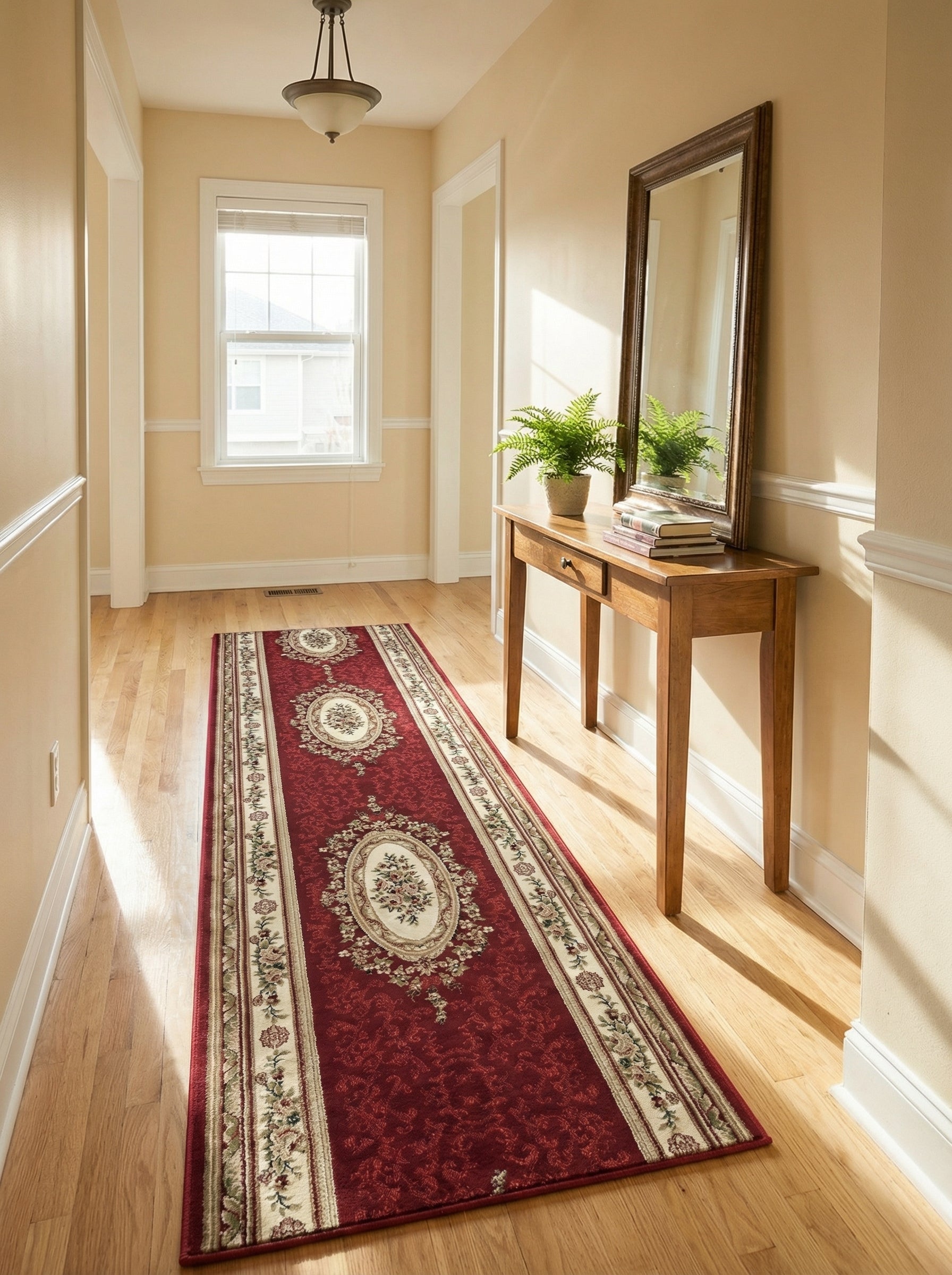 Tapis de couloir rouge bordeaux à motifs floraux et médaillons crème, posé sur un parquet clair dans une entrée ensoleillée