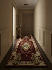 Tapis de couloir rouge bordeaux aux riches motifs floraux crème, or et vert, posé sur un plancher de bois foncé dans un élégant couloir