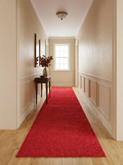 Tapis coureur rouge vif à la texture douce et aux motifs subtils, posé sur un parquet clair dans un couloir classique