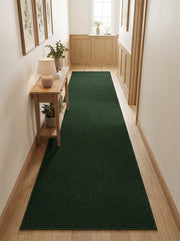 Long tapis de couloir vert foncé uni à poils courts, posé sur un parquet en bois clair dans une entrée
