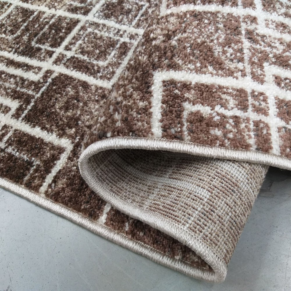 Tapis brun moucheté et blanc crème à motifs géométriques, texture à poils courts, enroulé sur un côté