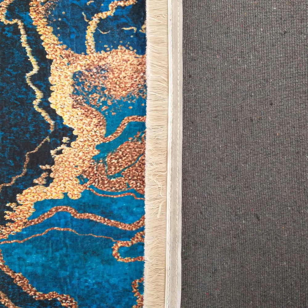 Tapis aux motifs abstraits dorés sur fond bleu intense, avec des franges crème et un envers tissé gris foncé