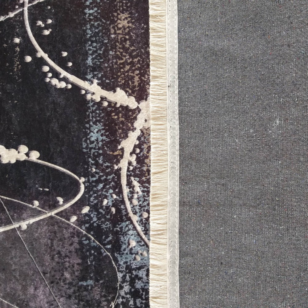 Tapis à surface veloutée noire et bleu-gris avec motifs éclaboussés blancs, bordure frangée claire, et envers tissé gris
