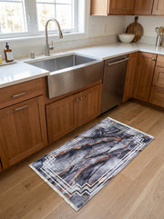 Tapis rectangulaire gris foncé marbré avec des veines dorées et un cadre géométrique blanc. Posé sur un parquet dans une cuisine