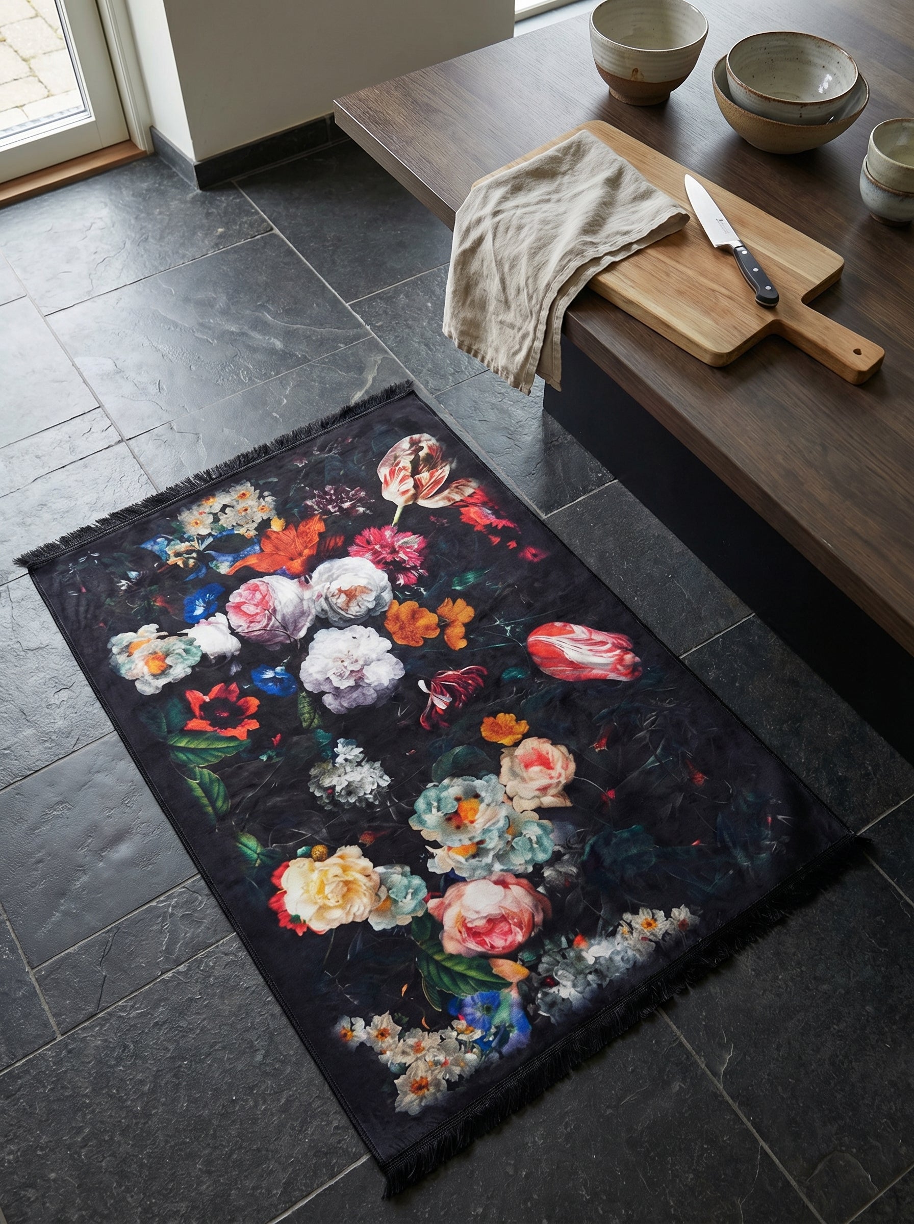 Tapis rectangulaire à franges, motif floral inspiré des natures mortes hollandaises sur fond noir, posé dans une cuisine
