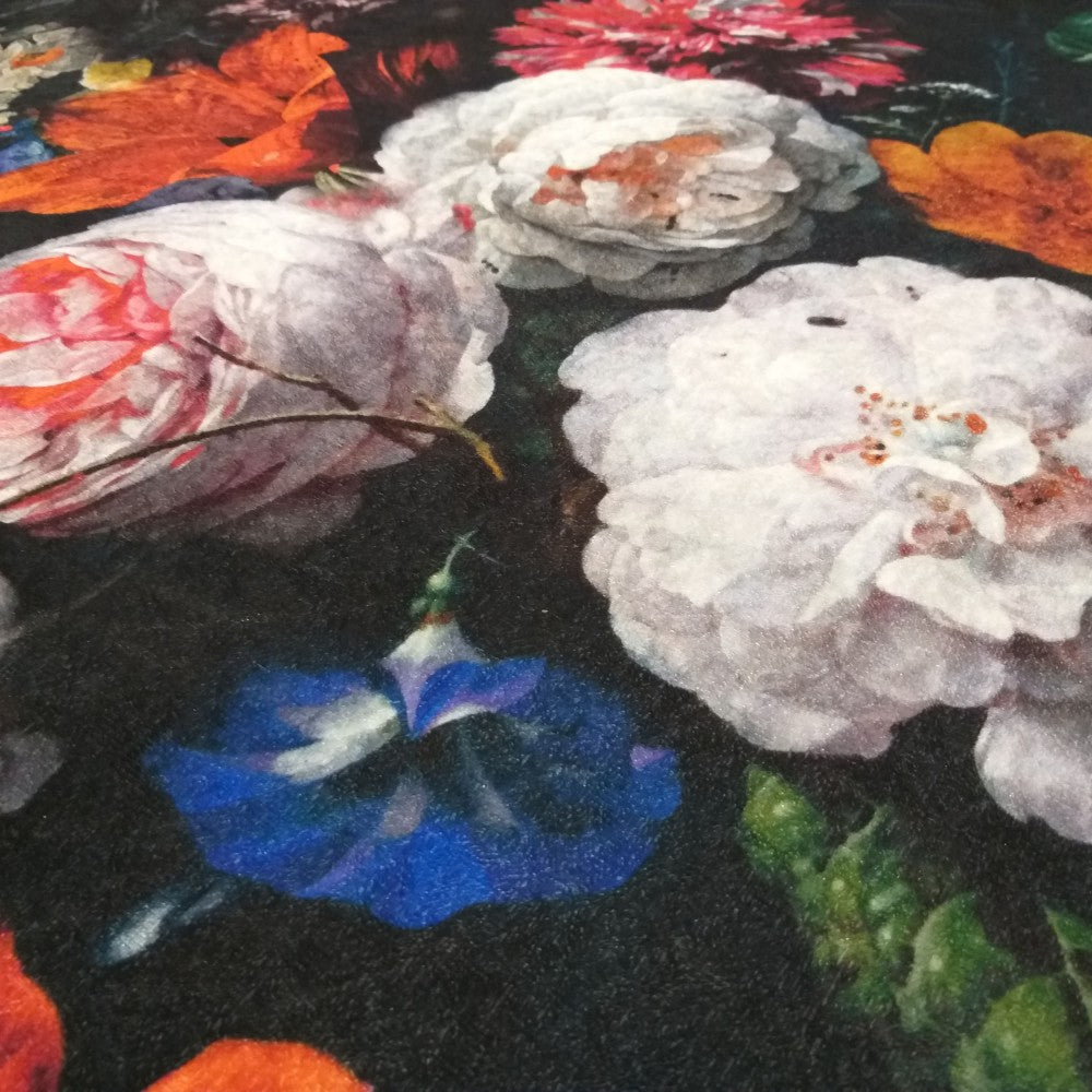 Tapis aux motifs floraux foncés. On y voit de grandes roses blanches, une fleur bleue et des feuilles orangées