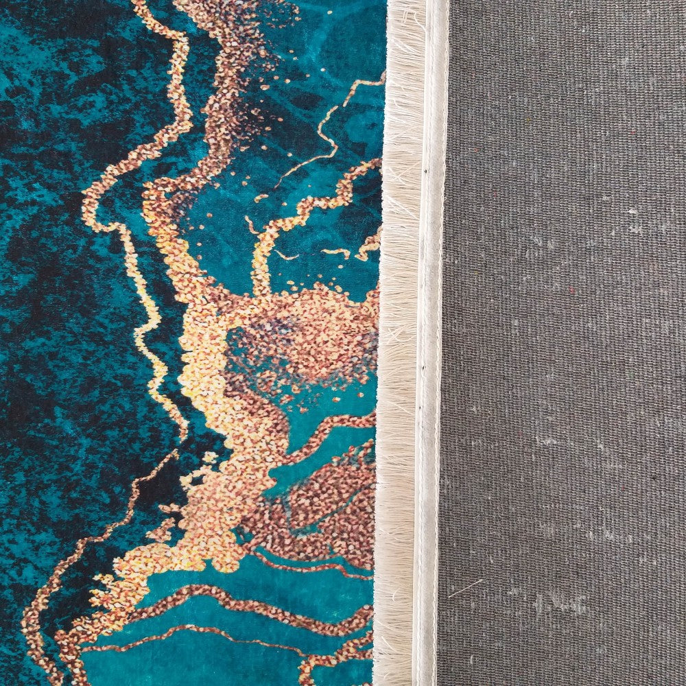 Tapis en velours à motifs marbrés bleu-vert et or granuleux, avec une frange claire et un dos gris