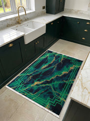 Tapis rectangulaire vert foncé et bleu avec des motifs marbrés dorés et une bordure géométrique verte, posé sur un carrelage clair dans une cuisine