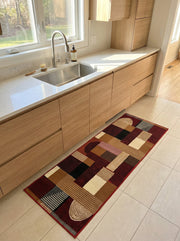 Tapis runner à motifs géométriques complexes (rectangles, rayures, cercles), couleurs bordeaux, marron, beige, noir, dans une cuisine