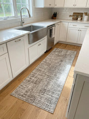 Tapis de couloir rectangulaire gris et blanc aux motifs abstraits et texturés posé sur un parquet en bois clair dans une cuisine moderne