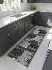 Chemin de tapis rectangulaire aux motifs abstraits et texturés en noir, gris clair et blanc, sur le carrelage d'une cuisine