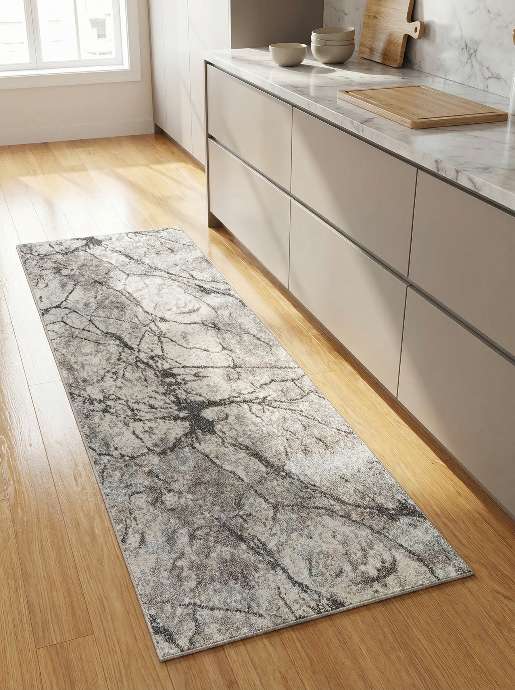 Tapis rectangulaire aux motifs marbrés abstraits gris et blanc cassé posé sur un parquet en cuisine