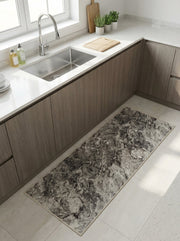 Tapis de cuisine allongé aux motifs marbrés dans les tons de gris, devant un évier moderne