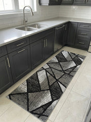 Tapis de couloir rectangulaire à motifs géométriques noir et gris variés, posé sur le carrelage clair d'une cuisine moderne