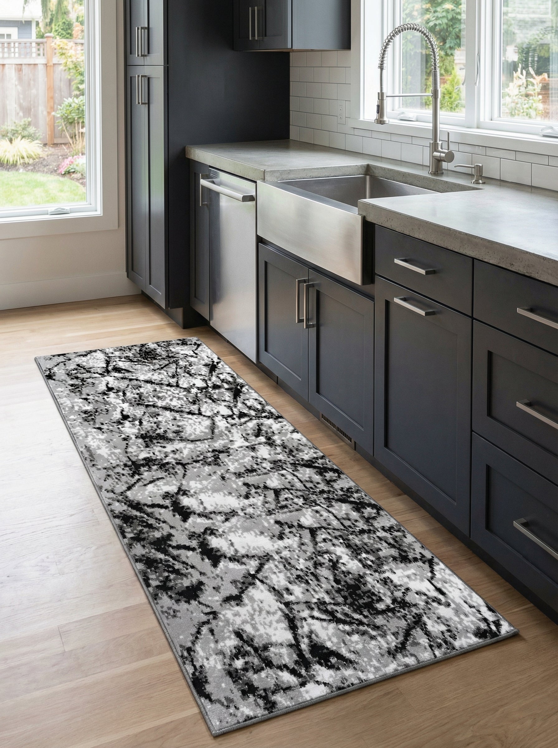 Tapis de couloir rectangulaire aux motifs abstraits noirs, gris et blancs sur un sol en bois clair dans une cuisine moderne