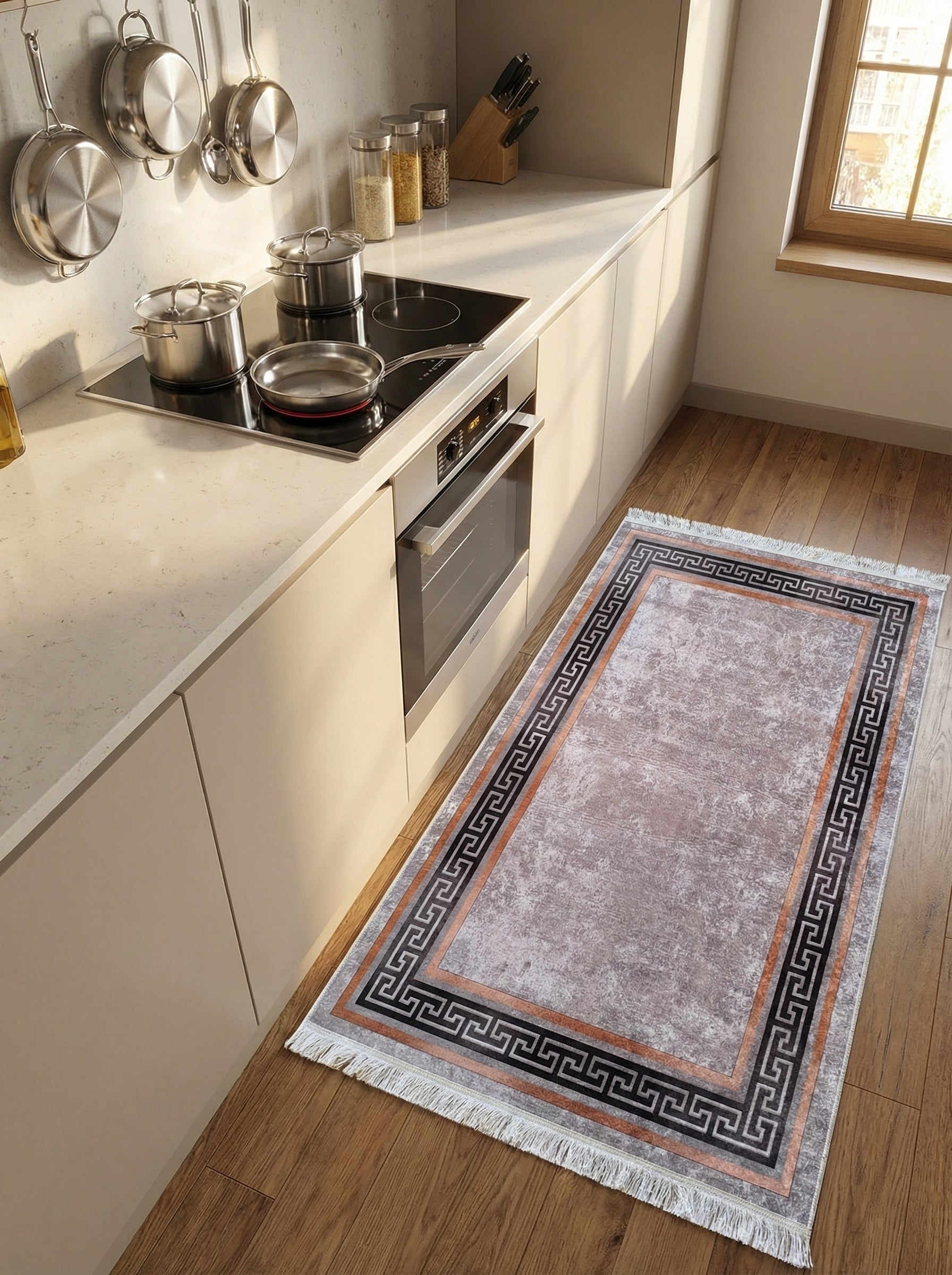 Tapis rectangulaire gris texturé avec un motif méandre grec noir et une bordure cuivrée, posé sur un parquet dans une cuisine lumineuse