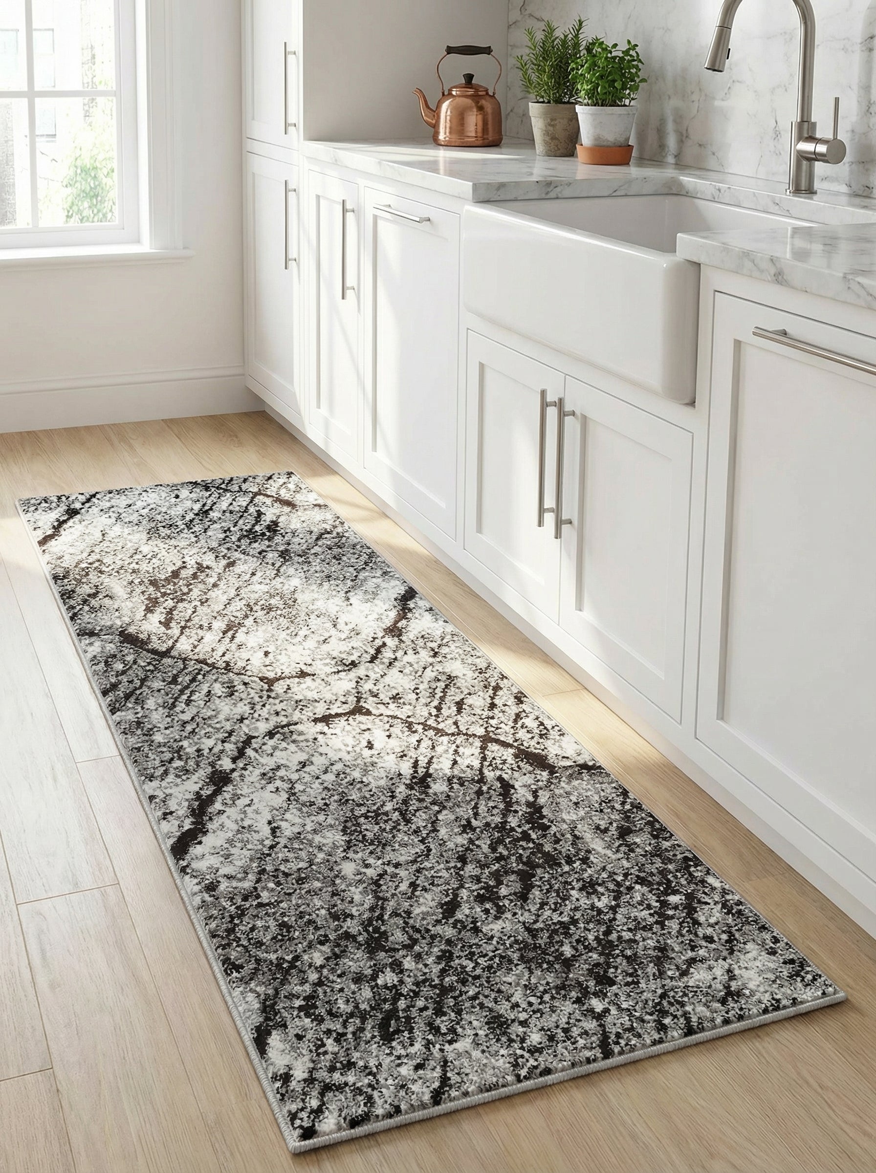 Long tapis rectangulaire aux motifs abstraits marbrés noirs, gris et blanc cassé, posé sur un parquet clair dans une cuisine moderne