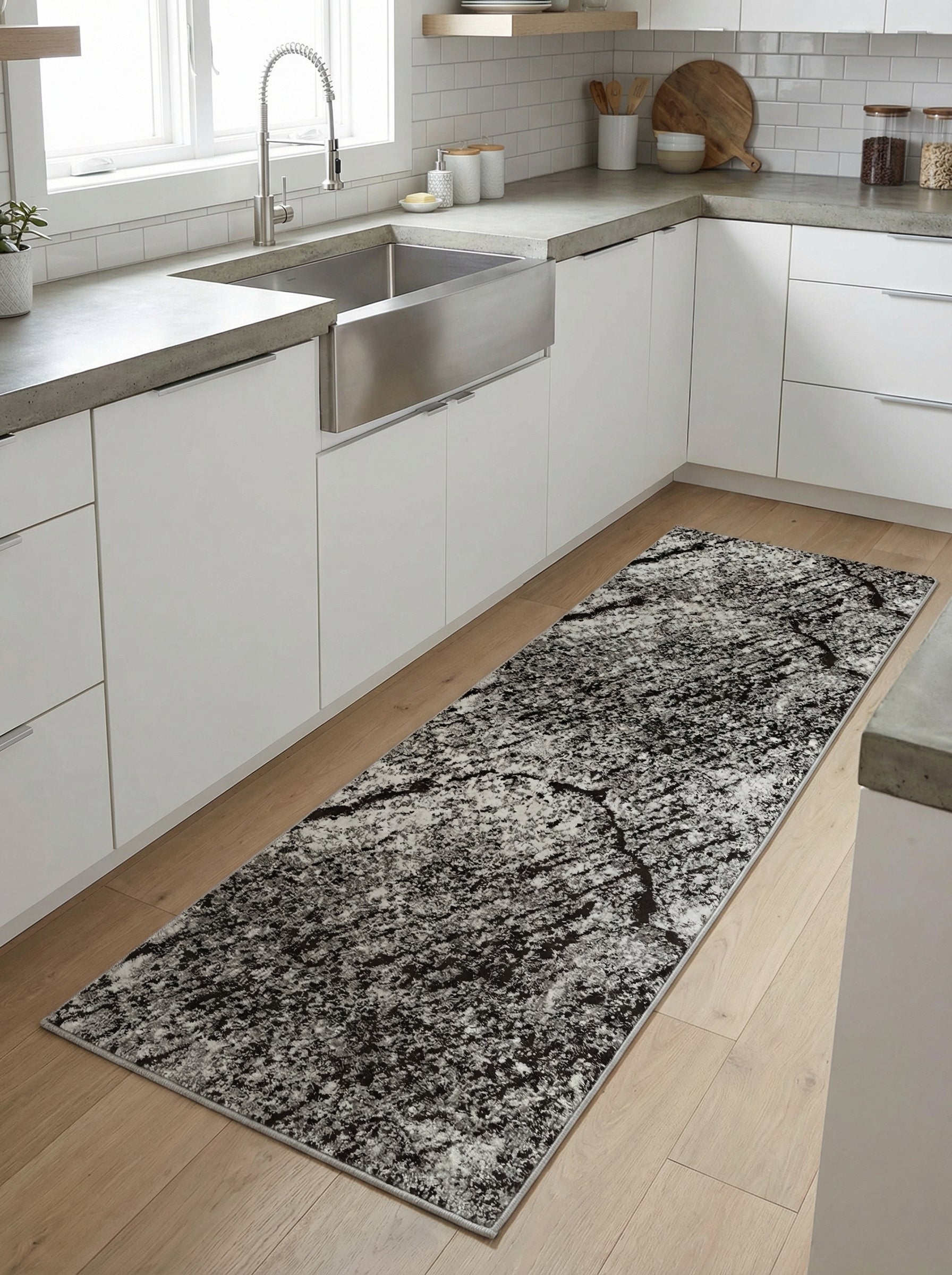 Chemin de tapis rectangulaire aux motifs abstraits gris charbon et blancs, effet marbré usé, sur un parquet en bois clair dans une cuisine