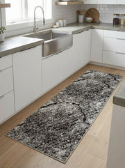 Chemin de tapis rectangulaire aux motifs abstraits gris charbon et blancs, effet marbré usé, sur un parquet en bois clair dans une cuisine