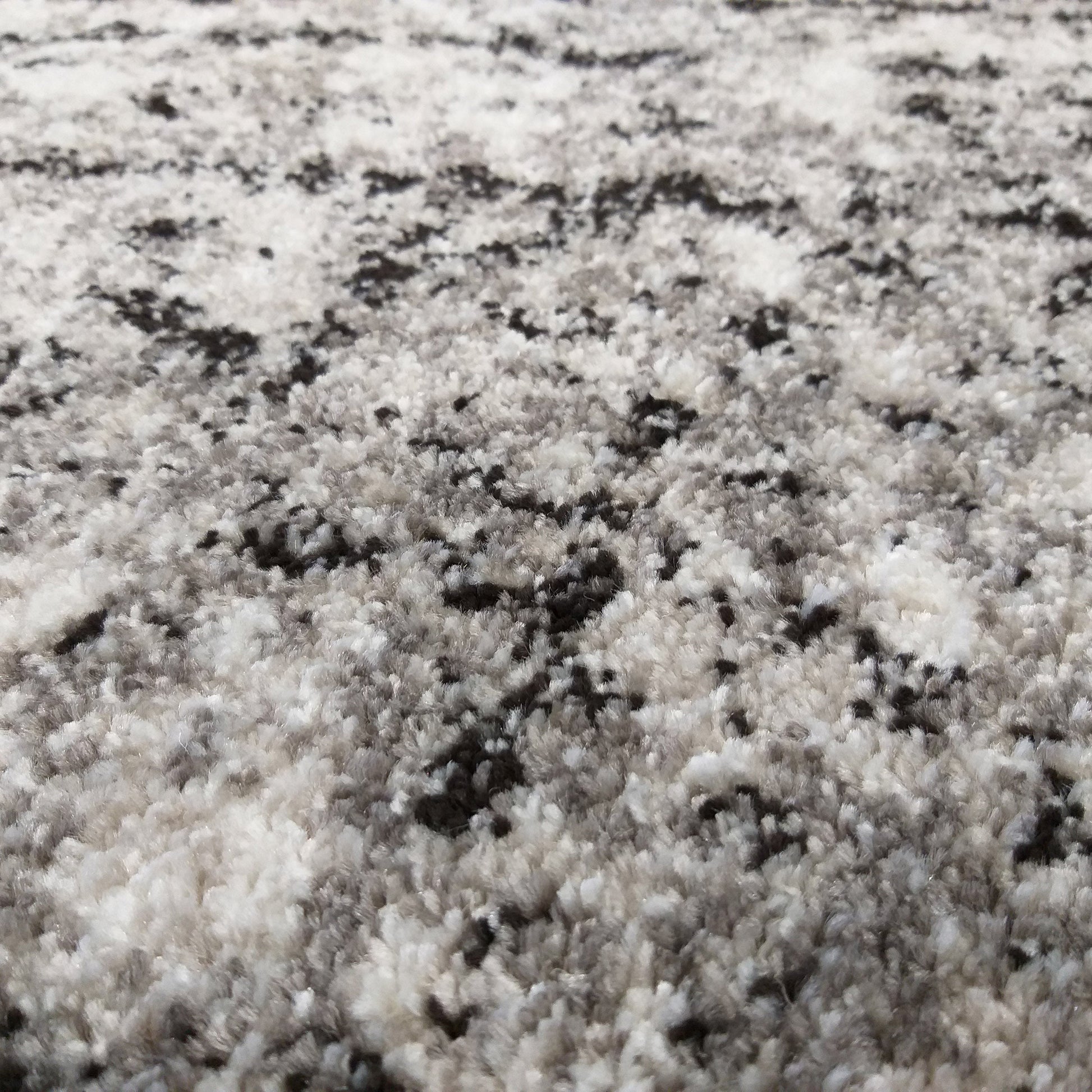 Tapis à poils longs avec un motif abstrait mêlant des fibres blanches, grises et noires