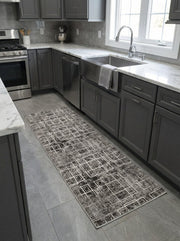 Tapis de couloir gris foncé, noir et blanc, à motifs géométriques de lignes entrelacées, sur un sol carrelé dans une cuisine moderne