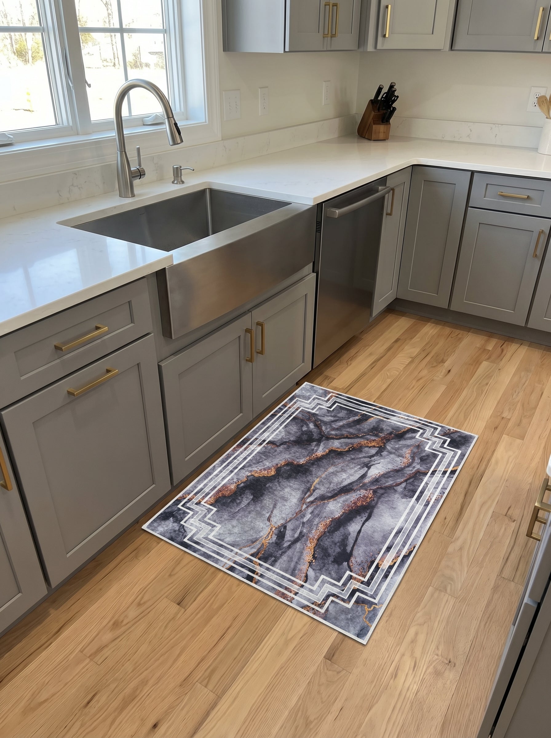 Tapis rectangulaire aux motifs marbrés gris, noirs et dorés, avec un cadre géométrique blanc, sur un parquet clair de cuisine