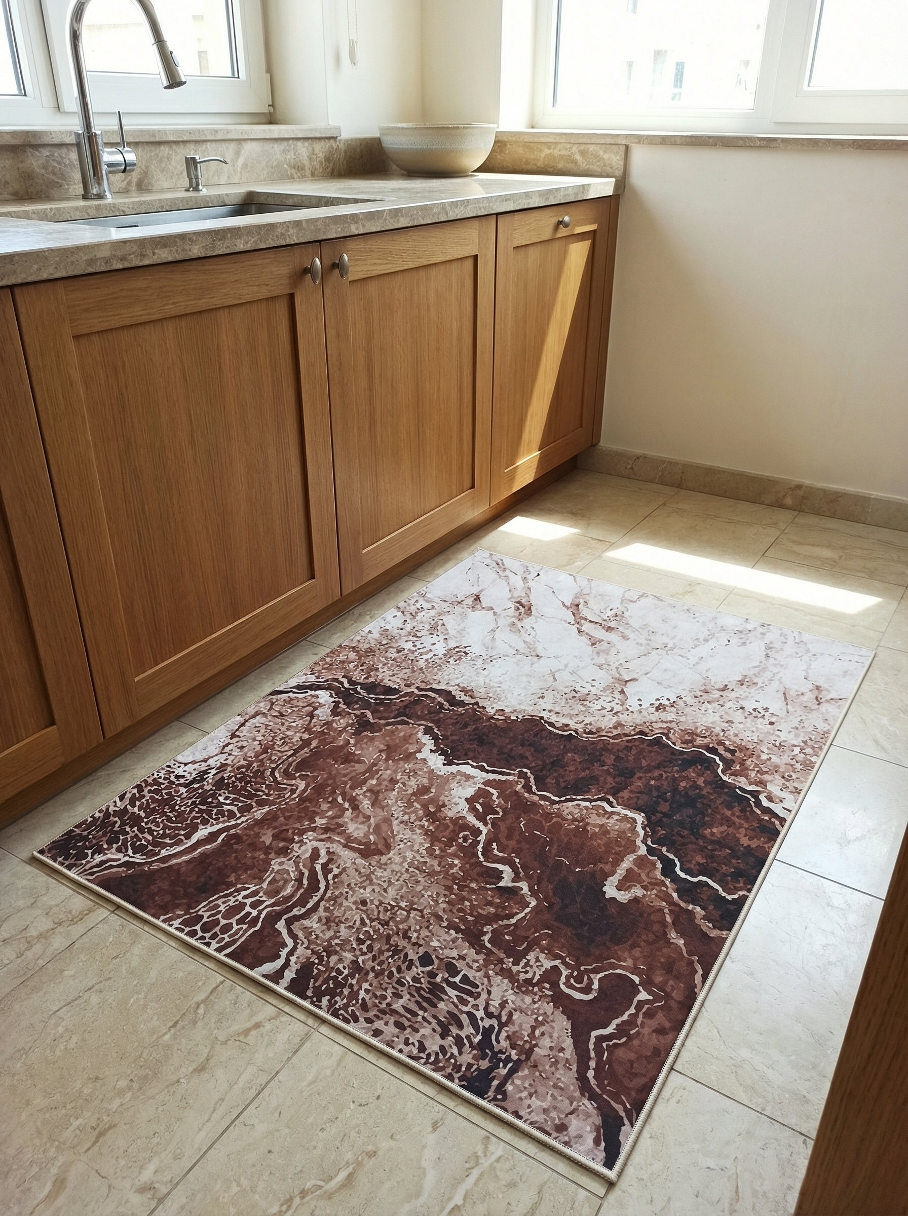 Tapis rectangulaire à motifs abstraits marron foncé, rouille et blanc crème, évoquant la roche ou le marbre, dans une cuisine aménagée
