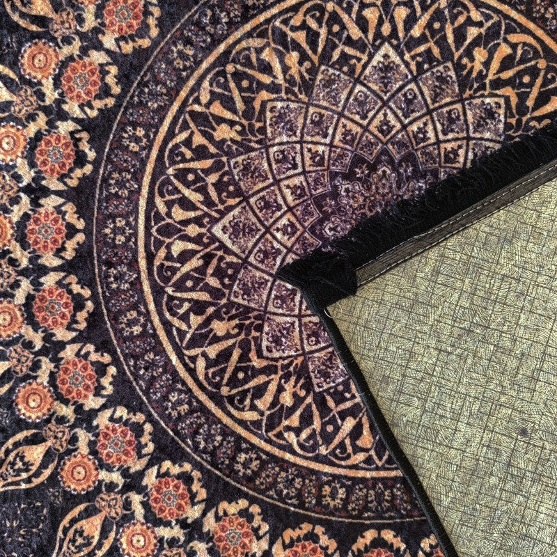 Tapis moelleux aux motifs orientaux noir et orange, bordé de franges noires, avec l'envers texturé beige visible