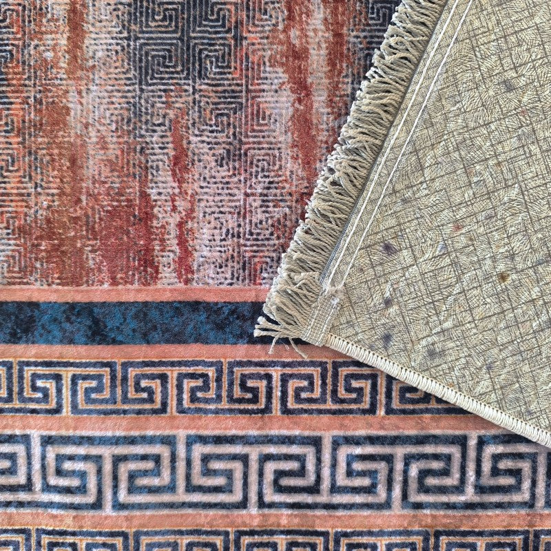Tapis aux motifs abstraits rouge-brun et noir. Bordure à clé grecque bleu-vert sur fond pêche. Le revers beige clair et les franges sont visibles