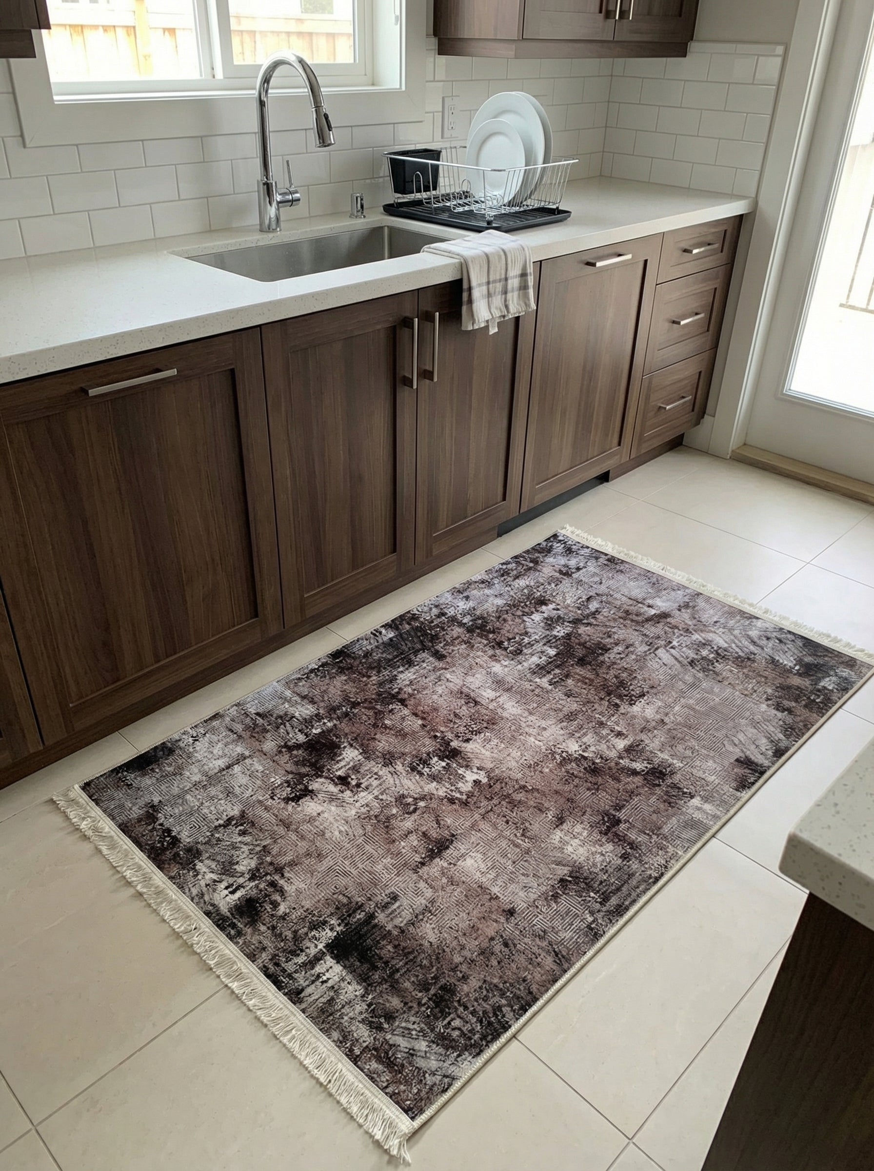Tapis rectangulaire à motifs abstraits et géométriques gris, marron et crème, avec franges claires, au sol d'une cuisine