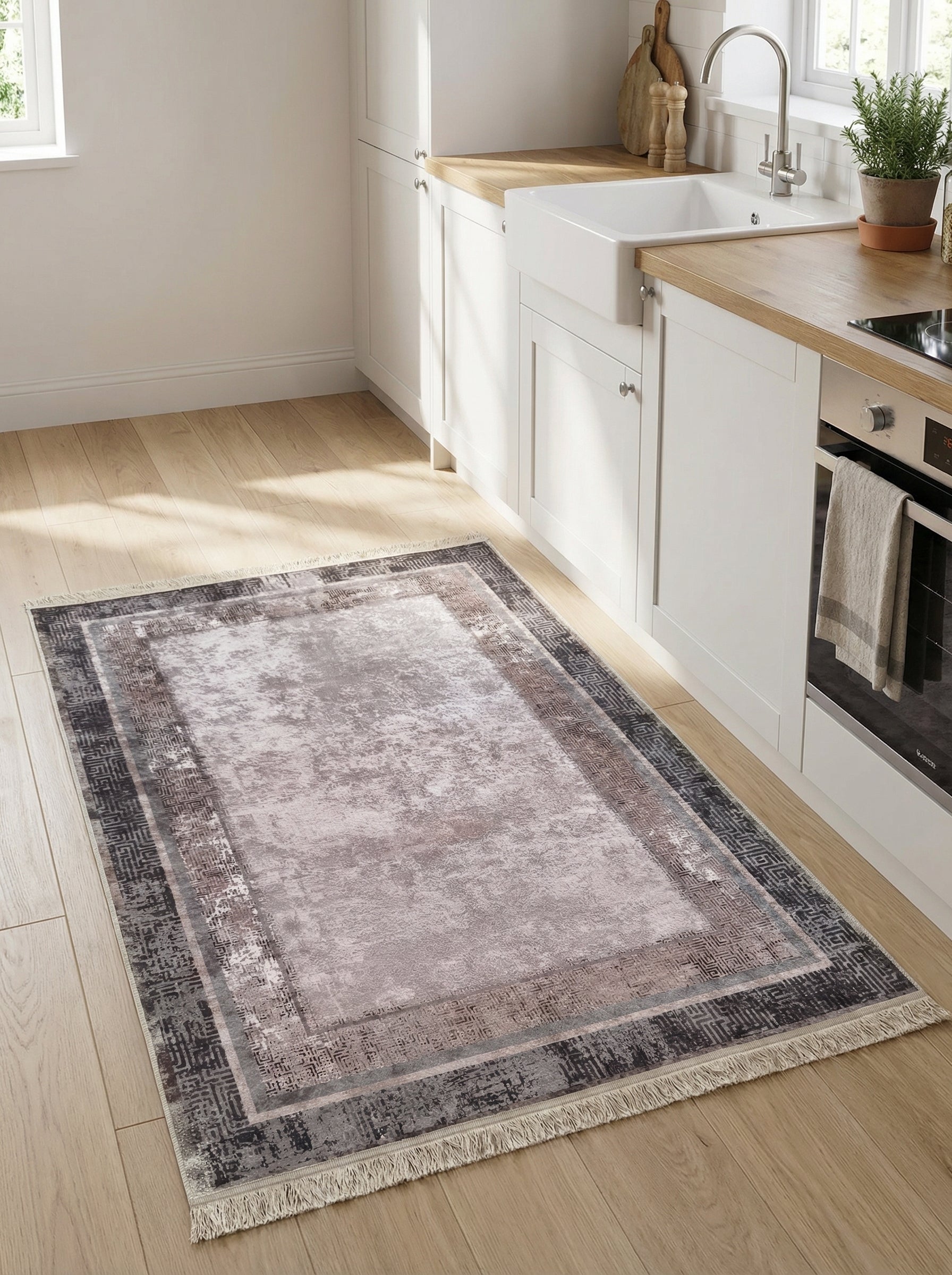 Tapis rectangulaire beige-gris délavé avec bordures marron et foncées à motifs géométriques, agrémenté de franges claires, dans une cuisine