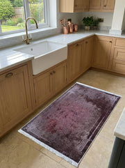 Tapis rectangulaire lie de vin et gris patiné, orné d'une bordure de motifs géométriques et floraux, avec franges, dans une cuisine