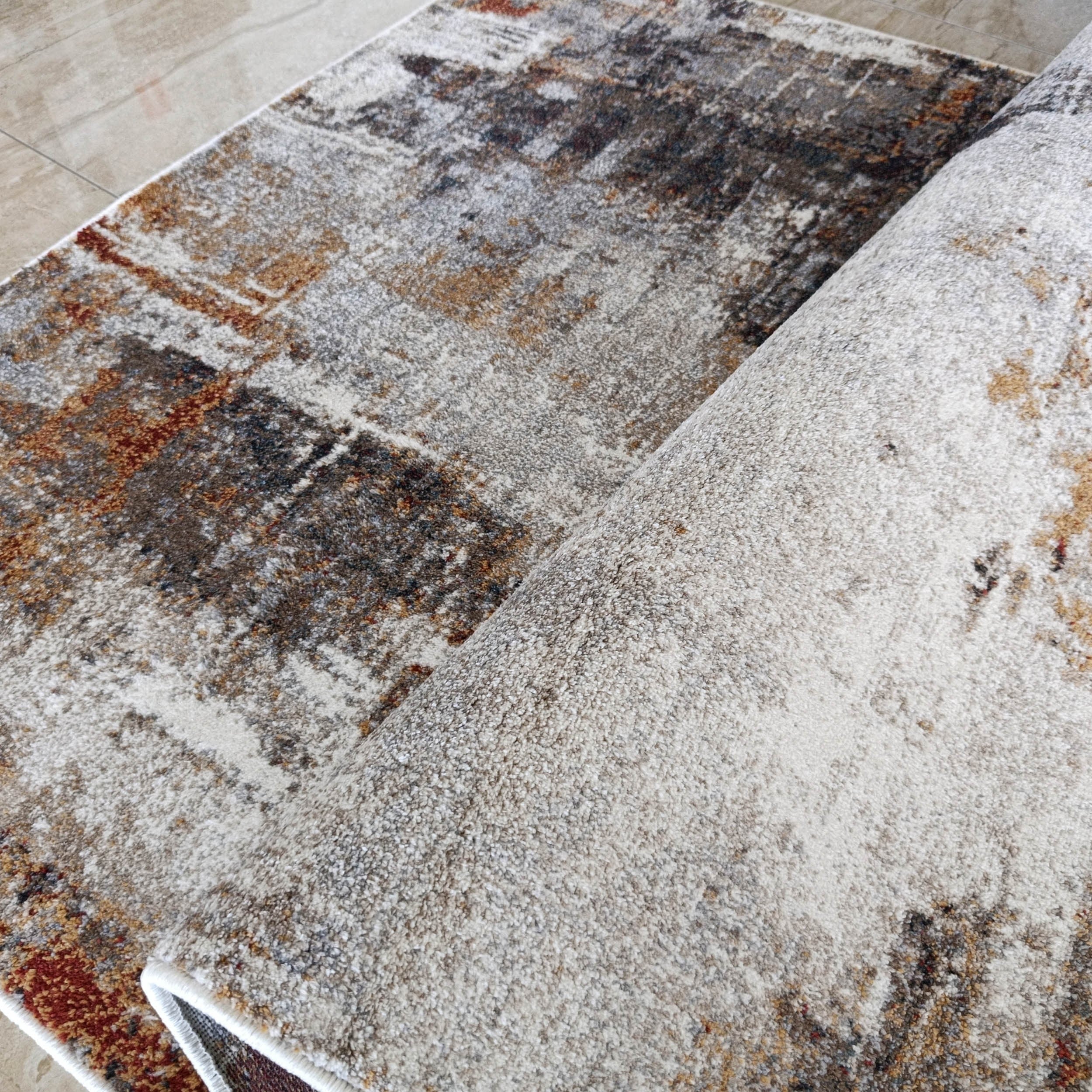 Tapis moelleux à motifs abstraits gris, blanc, brun roux et beige sur carrelage clair