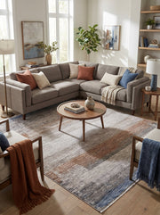 Tapis rectangulaire tissé aux motifs abstraits de larges bandes délavées gris clair, terracotta et bleu, dans un salon
