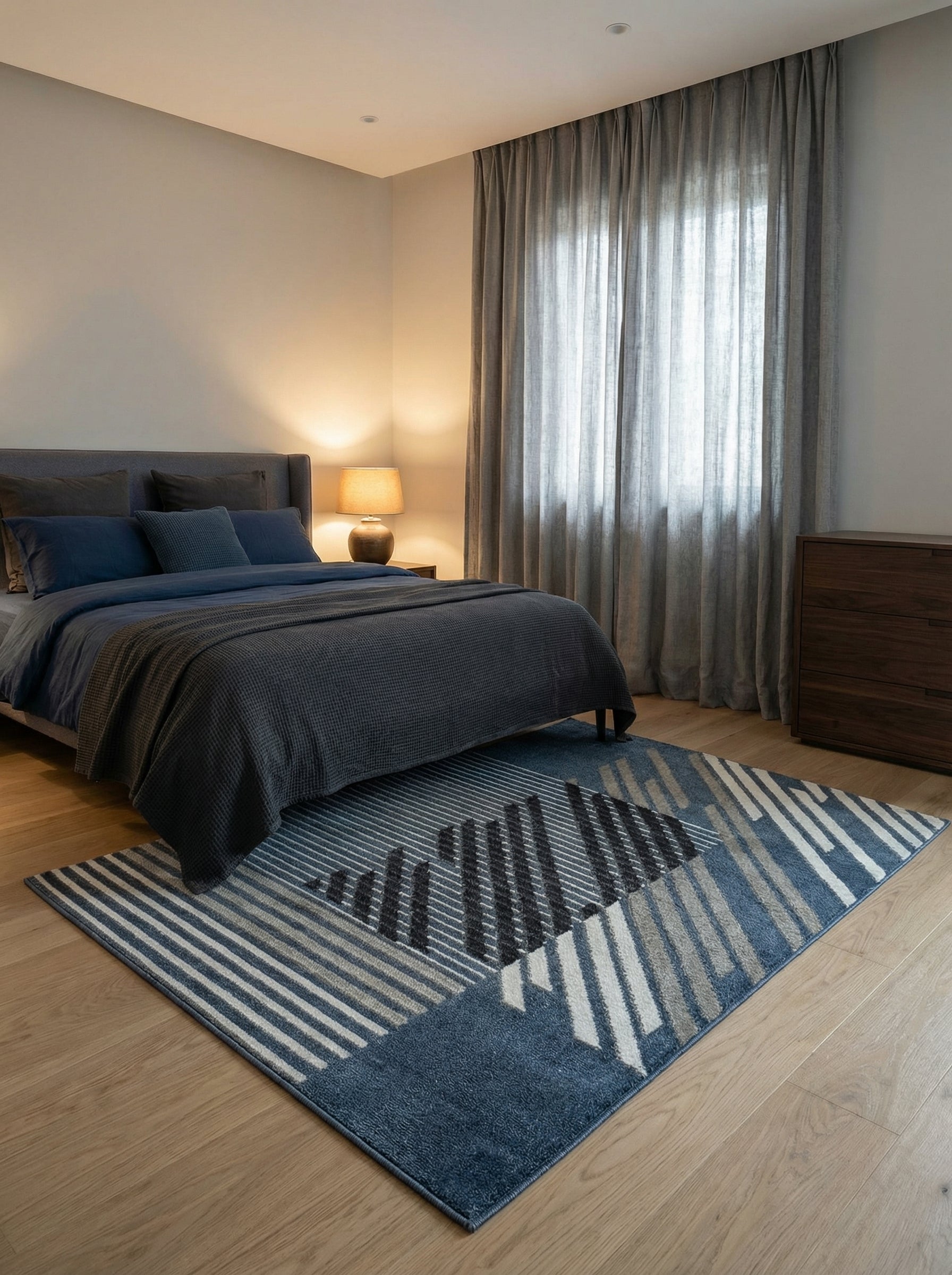 Tapis rectangulaire à motifs géométriques de blocs et fines rayures obliques bleus, gris et blancs dans une chambre