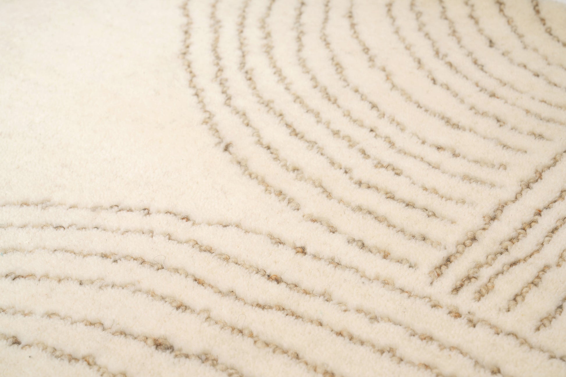 Détail texture d'un tapis beige fait main en laine. Zoom sur les fibres et le tissage rectangulaire.